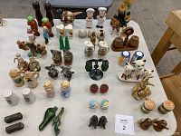 Wide view of 31 vintage salt and pepper shaker sets displayed on table, showing variety of materials and shapes including animals and figurines