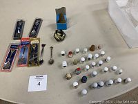 Photo showing layout of 30 vintage thimbles with different materials along with 7 collector spoons and one glass paperweight.