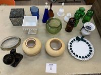 Overview of lot showing variety of colored glassware including green, brown, blue glass, white milk glass, pottery, and small decorative items on table