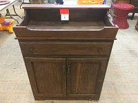 Front view of closed vintage wooden cabinet with drawer and double doors.