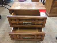 Two vintage wooden nightstands with two drawers each, geometric carved drawer fronts and metal handles shown from front and top drawer opened.