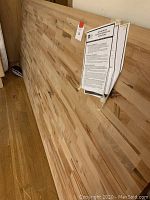 Full view of butcher block countertop leaning against wall with installation instructions taped on side