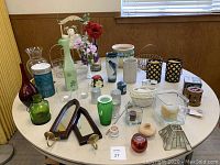 Wide angle photo showing all decorative items arranged on round white table, including vases, candle holders, floral figurines, and various small decorative containers.