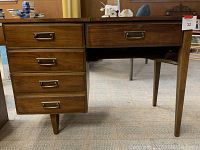 Front view of vintage wooden sewing cabinet showing three drawers on left and space for sewing machine on right.
