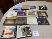 Overall view of all 14 vintage reel-to-reel tapes in original cardboard boxes arranged on table.