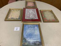 Set of five framed Christmas wall art pieces arranged on a table including four sheet music prints and one lace angel art piece.