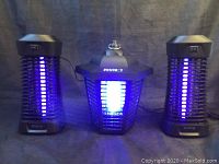 Three electric bug zappers arranged together, all powered on with glowing UV lights. One in center is Pestnot brand with hexagonal lantern style. Two on sides are EndBug brand with cylindrical shape.