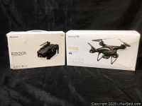 Original retail boxes for Eachine E520S and Snaptain SP650 drones on black background