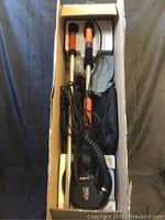 Full contents of open box: drywall sander tool, extension rods, dust hose, sanding discs and carry bag in styrofoam packaging