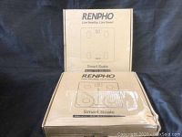 Two Renpho smart scales in original brown cardboard boxes, stacked vertically. Boxes show printed markings and model numbers ES 26M WB and ES CS20M.