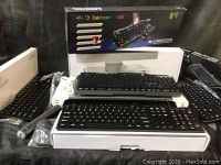 Full lot showing multiple keyboards including rainbow backlit Victsing wireless keyboard with mouse, mini design keyboards and wired keyboards arranged on a dark fabric background.