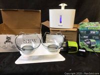 Wide shot of all items: double cat bowls on stand, Parner pet fountain, and automatic feeder with packaging.