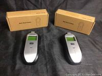 Two Tavool electronic wall stud finder devices displayed in front of their brown cardboard boxes, showing their overall shape and branding.