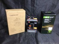 Photo showing three boxed items: portable camping fan, rechargeable LED camping lantern, and solar LED lantern.