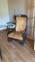 Front and side view of the rocking chair showing striped upholstery and mahogany frame.