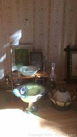 Photo of decorative bowls, gas lamps, and wooden stool displayed together