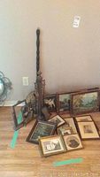 Photo showing the brass fireplace tool set with long wooden handle brass bed warmer and several framed antique prints in varied sizes laid on the floor.