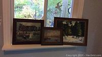 Three framed oil paintings displayed on a windowsill, showing size and condition of frames and artwork.