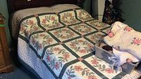 Full bed showing handmade floral quilt covering it