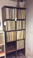 Wide view of wooden shelves holding hundreds of vinyl records with visible wear.