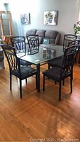 Full dining set showing glass table and six chairs on hardwood floor