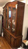Side view of wood-framed china cabinet showing glass front doors and profile