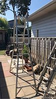Fully extended silver aluminum ladder in straight extension mode outdoors with visible marks and rust spots on metal.