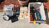 Photo of plastic tote filled with various hand tools, sanding sheets, drill bit set and accessories.