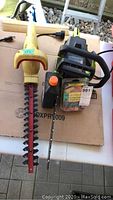 Image showing yellow McCullough electric hedge trimmer and green Poulan gas chainsaw side by side on cardboard surface.