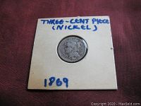 Front side of the coin showing a Liberty profile and handwritten labeling on holder (Three-cent piece nickel, 1869).