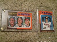 Front view of two vintage 1974 OPC baseball cards featuring players Steve Busby, Dick Bosman, Nolan Ryan, with '74 Highlights' header, in protective cases.