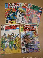 Five G.I. Joe comic books arranged on a wooden surface. Included are Tales of G.I. Joe issues #1, #11, #12; G.I. Joe European Missions #1; and G.I. Joe Special Missions #2. Covers show action scenes and characters in military attire.