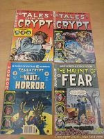 Four EC Comics reprint horror comic books laid out on a wooden surface: two Tales from the Crypt, one Vault of Horror, and one Haunt of Fear.