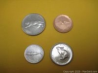Photo showing four Canada Centennial coins including 25 cents with bobcat, 1 cent with rock dove, 10 cents with mackerel fish, and 5 cents with rabbit.
