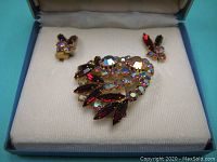 Set of vintage rhinestone brooch and clip earrings photographed inside original blue satin-lined box.