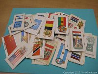 Pile of Brooke Bond collectible cards with visible colorful flags and emblems from various countries spread on a blue surface.