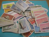 Broad view of a large pile of Brooke Bond tea/tobacco cards from "The Saga of Ships" series. Cards show sailing ships and steamships artwork with varied colored borders.