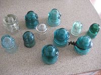 Overview photo of 11 vintage glass insulators in clear, blue, and green shades showing shapes and colors.
