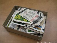 Box filled with stacked Brooke Bond Red Rose Tea collectible cards, showing card backs with print and some colored edges visible.
