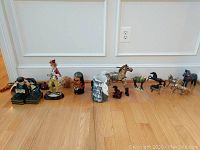 Wide shot showing all figurines including horses, clown, Japanese figurines and Raku vase lined up on floor.