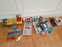 Full lot showing card tricks kit, assorted card decks, bubbles, games, and toys arranged on floor.