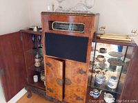 Full view of cabinet with glassware and porcelain items displayed inside, including Blue Willow teapot and Delft cannister.