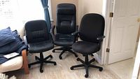 Three rolling swivel office chairs positioned side by side showing overall condition and styles.
