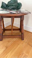 Side view of antique walnut round drop leaf table showing legs and lower stretcher with items on top.