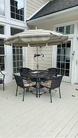 Full set of four chairs around round metal mesh table with central umbrella and weighted base on deck