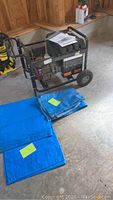 Generator and two folded blue tarps on garage floor