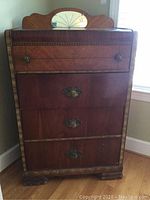 Full front view of the vintage wooden dresser showing four drawers with metal decorative handles and carved wood details.