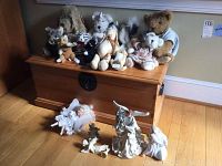 Full view of wooden trunk with multiple stuffed animals arranged on top and a few angel figurines positioned in front on the floor.