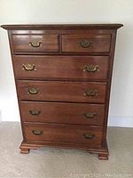Front view of solid cherry wood dresser showing six drawers and bracket feet.