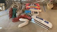 Lot showing multiple ropes in natural and synthetic fibers in various colors, two boat bumpers, radio control boat box, and small boxes including wrapping paper.